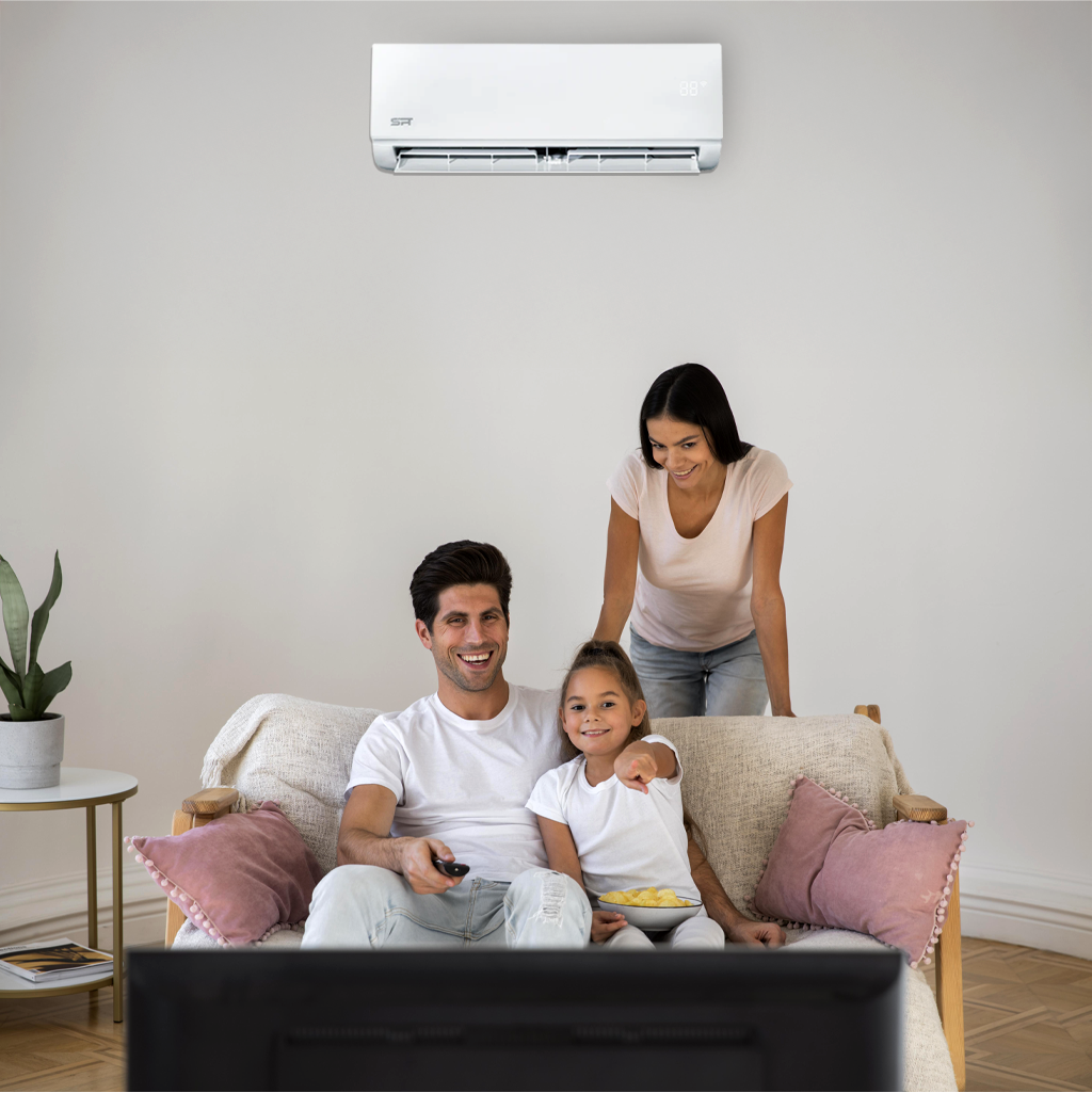 A family relaxes on a couch, with a TV and air conditioner present, highlighting their shared moments at home